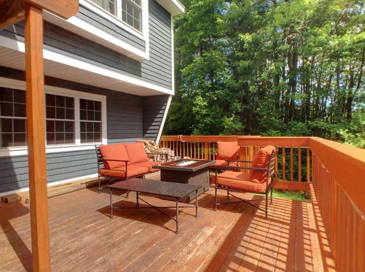A close-up of the outdoor dining area with bright orange cushions and a dark wooden table set against vibrant greenery. The space feels lively and communal, ideal for group dinners or informal strategy sessions, with the scenery hinting at memorable sunrise or sunset moments together.