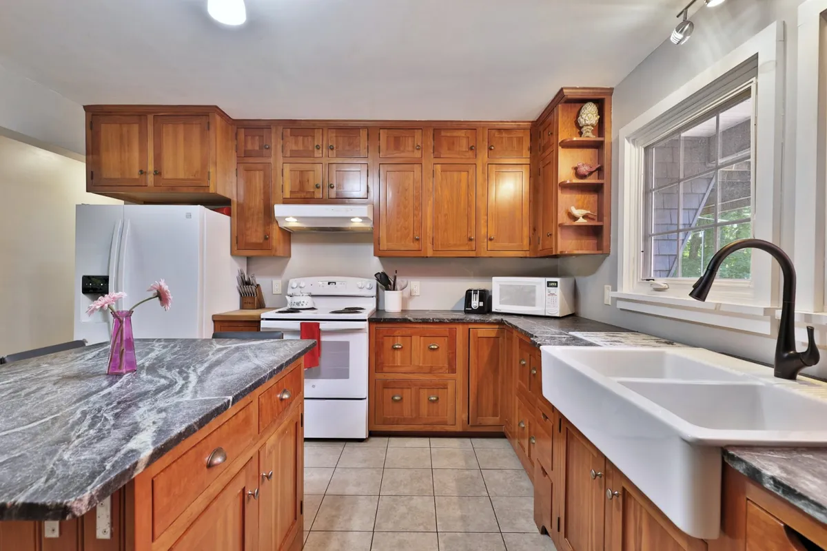 This image showcases a cozy, functional kitchen featuring a kitchen island, modern stainless steel appliances, a large sink, and warm wooden cabinetry. The setup invites cooking, baking, and family gatherings, reflecting a space where guests can prepare meals and share recipes together.