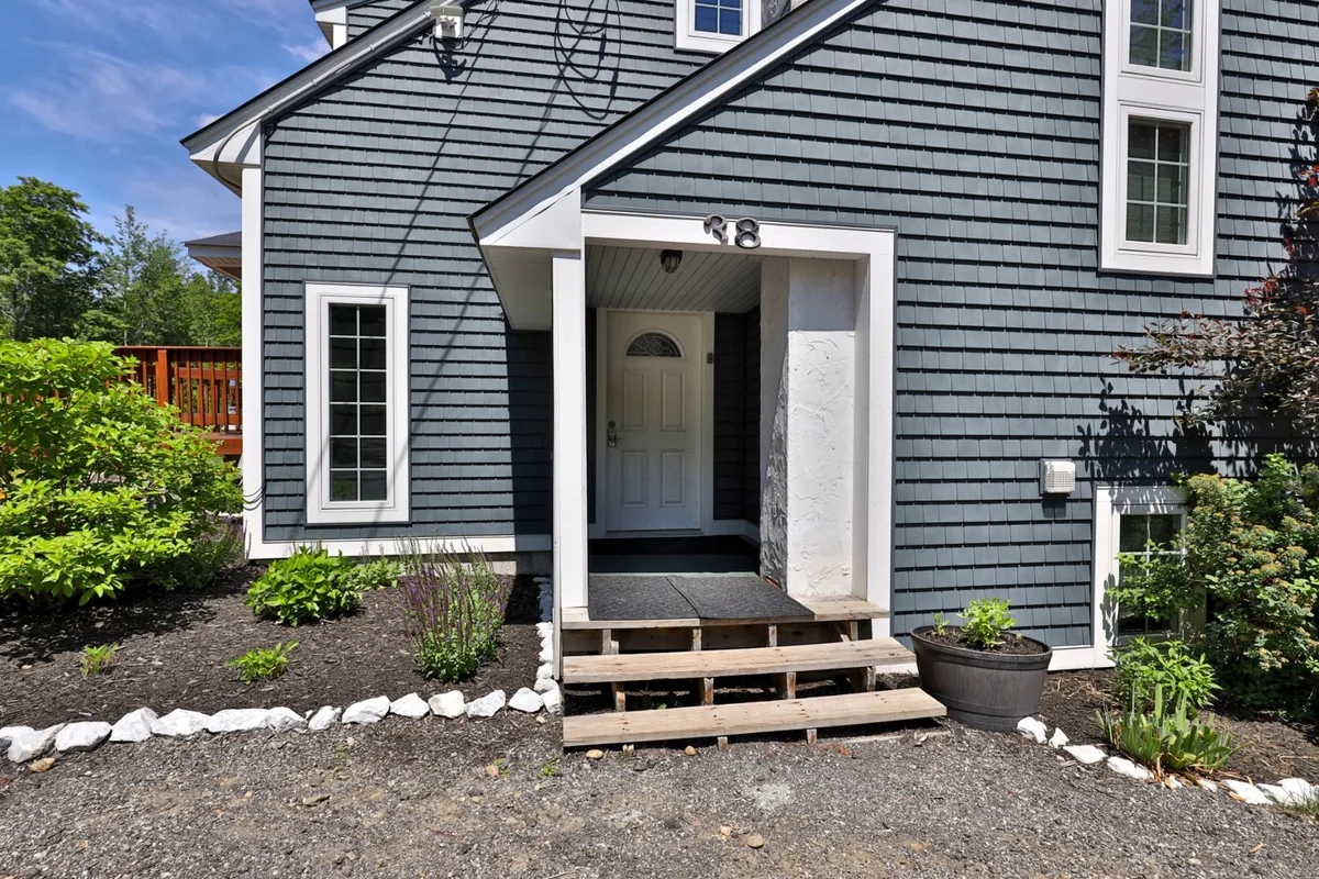 Captured is the front entrance of Bigelow Chalet, complete with wooden steps and a landscaped garden. The scene conveys a sense of arrival and welcome, setting the tone for special gatherings and first impressions as guests arrive for celebrations.