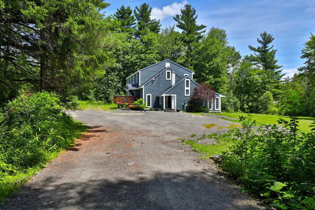 This image showcases the exterior of Bigelow Chalet with the house, driveway, and lush greenery surrounding the property. The spacious yard is visible, suggesting ample space for group gatherings, outdoor celebrations, and photo opportunities.