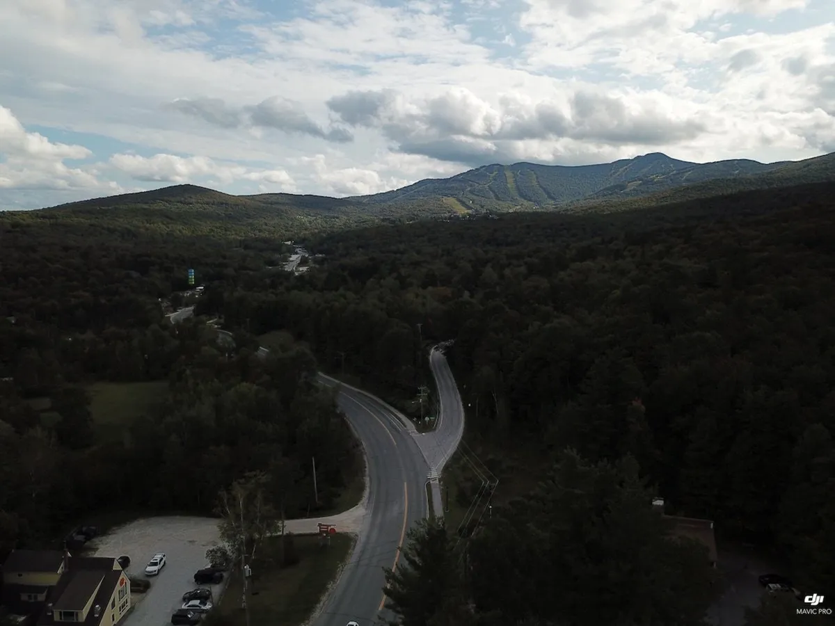 A scenic view of the surrounding Vermont mountains, a winding road, and trees—suggesting nearby opportunities for hiking, nature walks, and outdoor exploration.